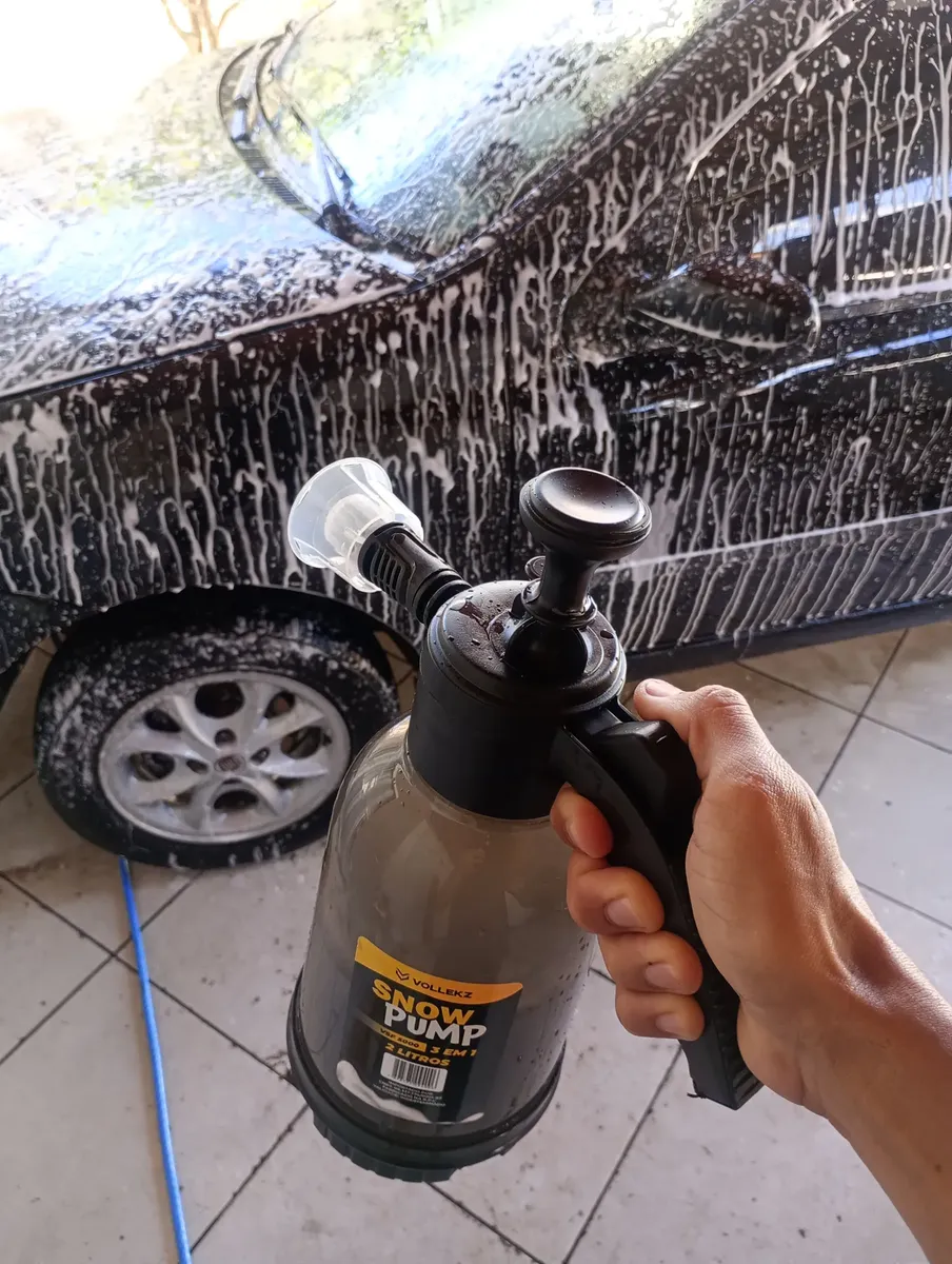 Cliente aplicando espuma na lateral de um carro preto com o pulverizador Snow Foam