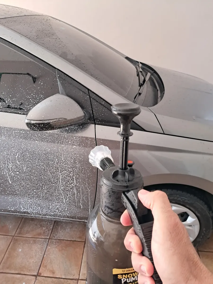 Carro cinza sendo lavado com espuma aplicada pelo pulverizador manual
