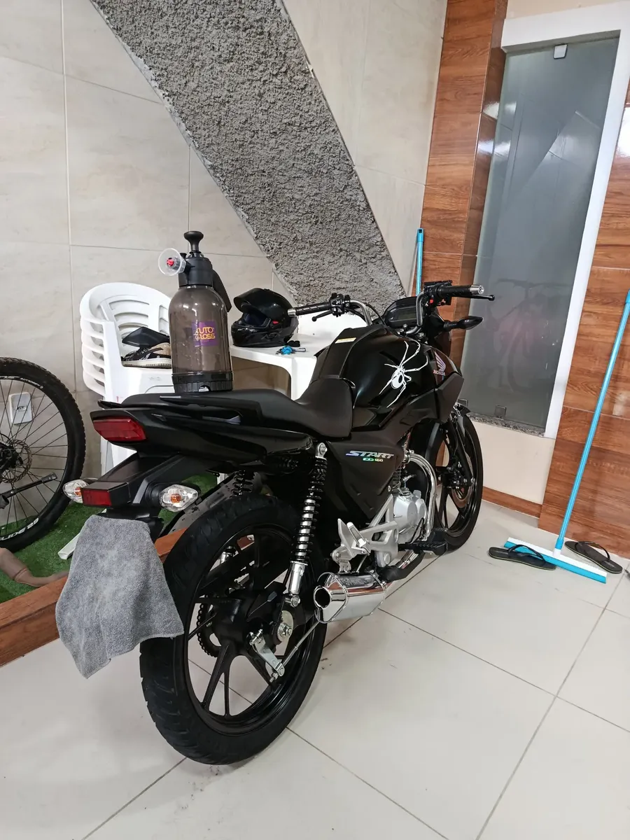 Pulverizador Snow Foam apoiado sobre uma moto preta em uma garagem